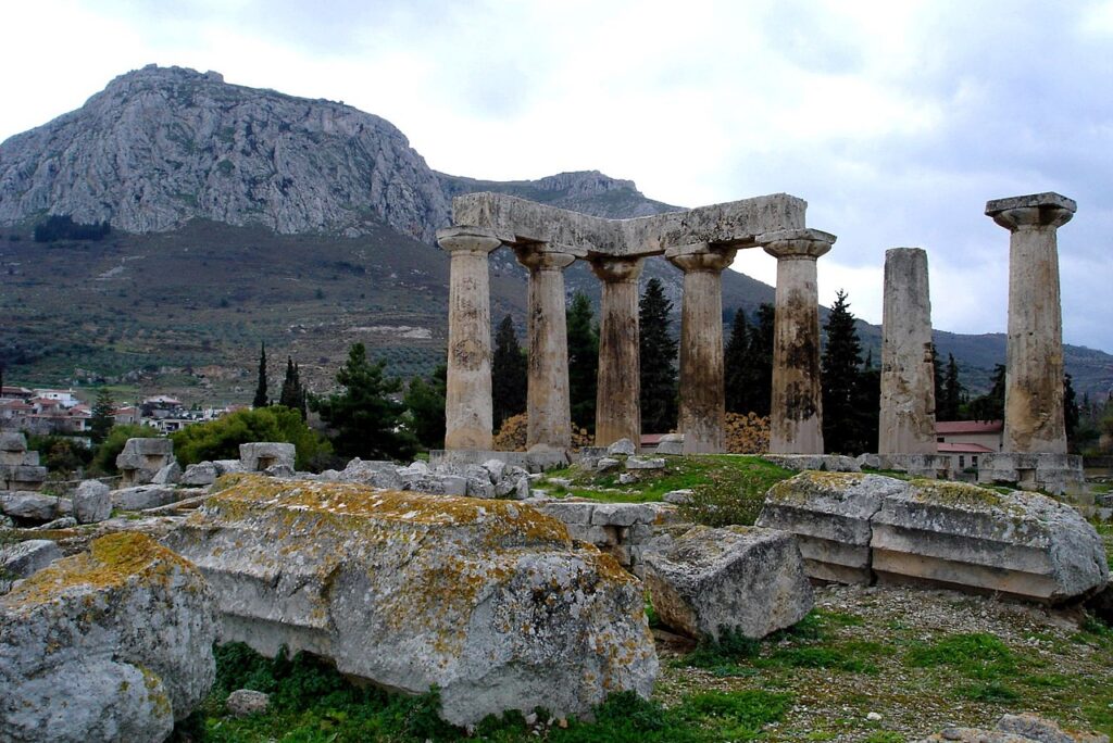 Ruins of the Temple of Apollo within the polis of Ancient Corinth, built c. 540 BC, with the Acrocorinth (the city's acropolis)